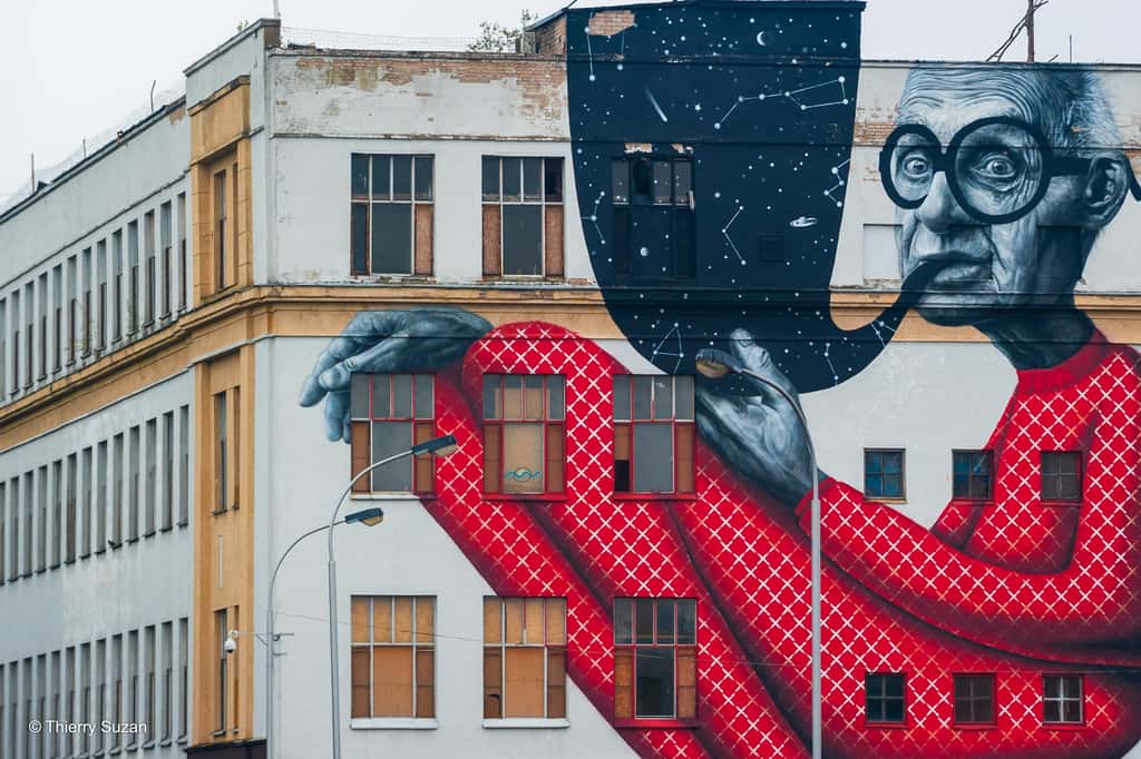 « Le vieux sage » est considérée comme la première fresque de grande envergure réalisée dans l'espace public en Lituanie. Elle met en scène Jurgis Mačiūnas, artiste natif de Kaunas et fondateur du mouvement Fluxus, représenté dans une posture décalée. Devenue une icône du street art lituanien, elle incarne à la fois le renouveau artistique et la métamorphose urbaine de la ville. Fresque de Žygimantas Amelynas, Kaunas © Thierry Suzan – Tous droits réservés